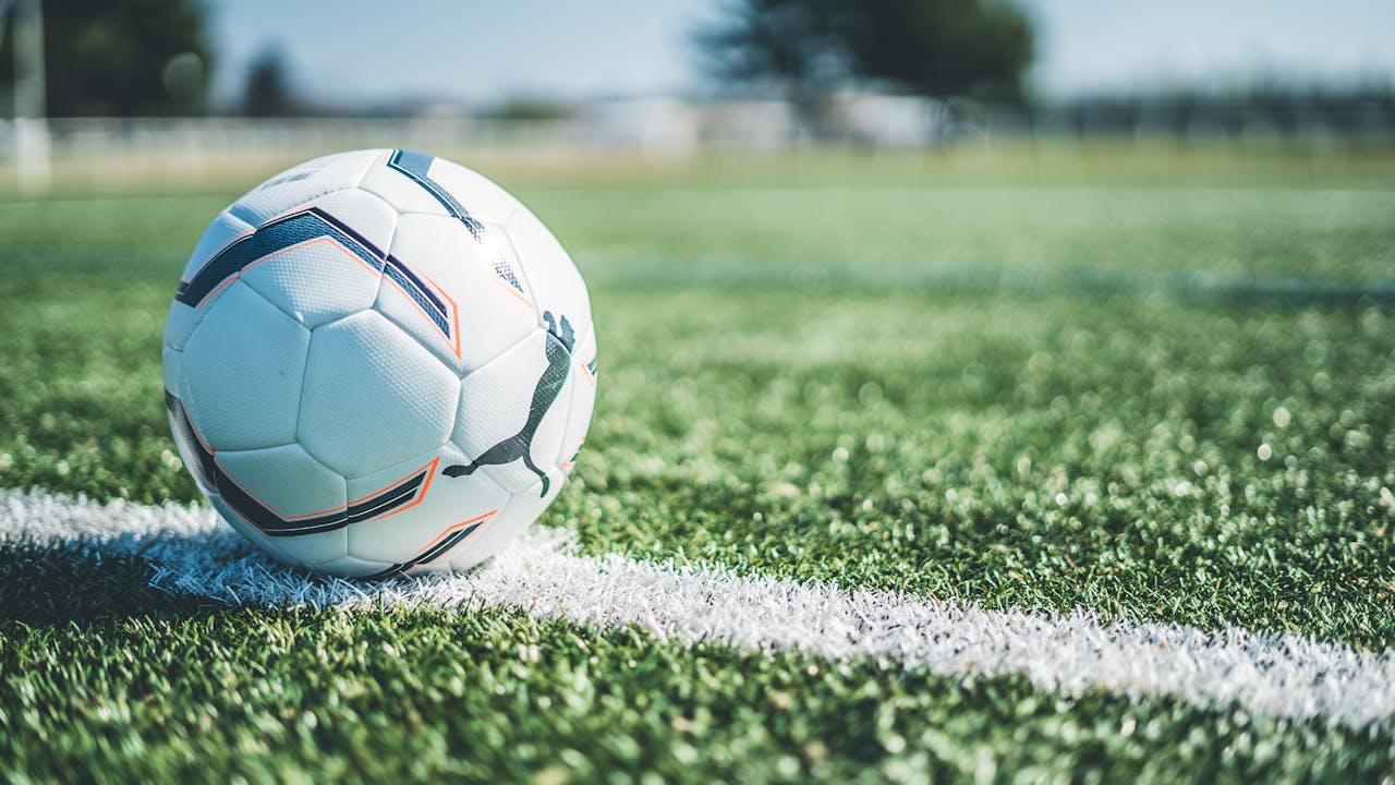 Soccer ball resting on white line of a green grass field. Perfect for sport themes.